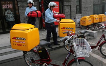 Employees carry delivery containers to their bicycles in Nanjing, Jiangsu Province, Jan. 18, 2007.