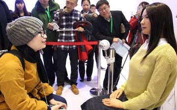 A visitor (left) interacts with Geminoid F, produced by renowned robot designer Hiroshi Ishiguro of Osaka University, during the World Robot Conference in Beijing, Nov. 23, 2015. 