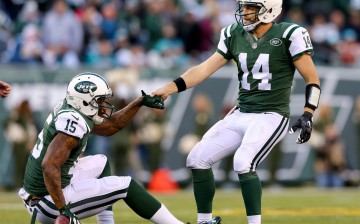 New York Jets quarterback Ryan Fitzpatrick (#14) helps up wide receiver teammate Brandon Marshall after a play against the Miami Dolphins.