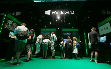 Attendees gather at Microsoft Corp.'s Windows 10 operating system exhibition stand at the Gamescom video games trade fair in Cologne, Germany, on Wednesday, Aug. 5, 2015. 