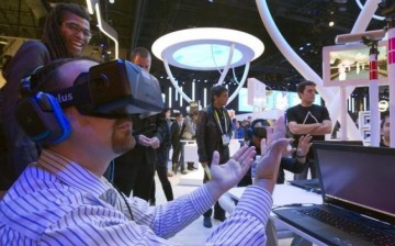 An attendee wearing an Oculus Rift virtual reality headset plays in a virtual volleyball game at the Intel booth during the 2015 International Consumer Electronics Show (CES) in Las Vegas, Nevada.