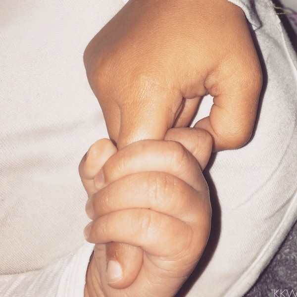 The tiny hand of the Saint West grasping the finger of older sister North West. 