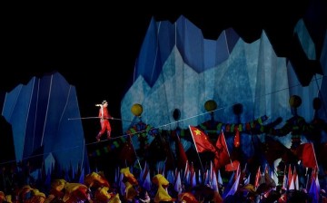 China's famous wire-walking artist Adli (top) carries the torch and walks on a wire during the opening ceremony of the 13th Chinese National Winter Games.