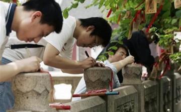 Students write wish cards for the upcoming National College Entrance Exam in a Confucius temple in Shanghai, June 5, 2008. 
