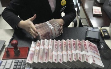 A clerk arranges bundles of 100 Chinese yuan banknotes at a branch of China Merchants Bank in Hefei, Anhui Province, March 17, 2014.