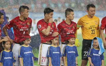 Players of Guangzhou Evergrande use their shirts to protect the ball kids from heavy rain during a match at Tianhe Sports Center in Guangzhou, China, on May 5, 2015.