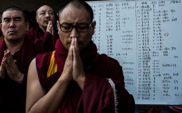 Monks pray near a list of the patients near a collapsed building in Tainan, Taiwan, on Feb. 7, 2016.