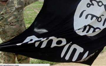 An ISIS activist displaying a flag of the terrorist organization.