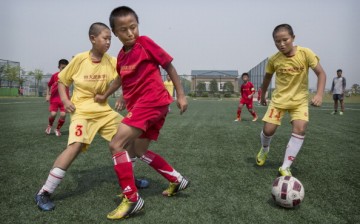 Young Chinese students play during a match on a practice pitch at the Evergrande International Football School on June 14, 2014 near Qingyuan in Guangdong Province, China.