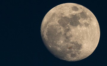 A plane flies past the moon at sunset in London, England, on March 3, 2015.