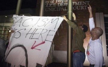 Protesters hang a banner against racism in a police precinct in Ferguson, Missouri.