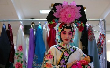 An artist of a Chinese opera troupe poses for a photo in the backstage.