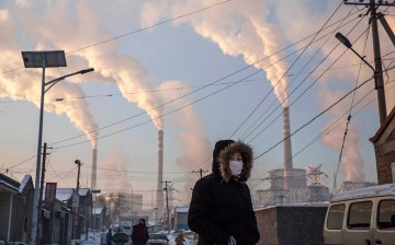 Smoke billows from stacks as a Chinese woman wears as mask while walking in a neighborhood next to a coal fired power plant on Nov. 26, 2015 in Shanxi, China.