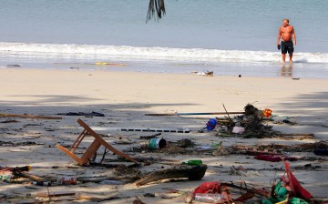 A Swedish tourist wades in the ocean along a garbage strewn and tsunami-struck beach December 27, 2004 in Phuket, Thailand.