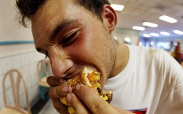 A man eats a burger in a hurry. 