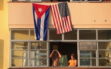 Cubans look out their window across the street from the newly reopened U.S. Embassy in hopes of watching the flag-raising ceremony in Havana, Cuba, Aug. 14, 2015.