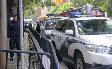 Police cars are parked as policemen stand guard outside a court in the southern Chinese city of Guangzhou, Jan. 29, 2016. 