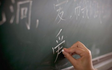 A teacher writes on a blackboard during a class for young earthquake survivors at a temporary housing area after the May 12 earthquake, June 1, 2008 in Dujiangyan, Sichuan Province, China.