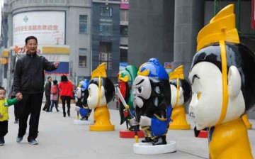 Locals walk by the cartoon figures of the Three Kingdoms period (AD 220-280) in front of a shopping mall in downtown Zunyi, Southwest China's Guizhou province, on April 1, 2016. 