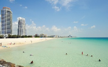 Vacationers enjoy the fine weather and the shallow clear waters of Miami Beach in Florida.