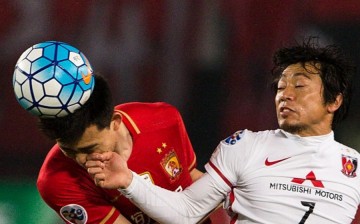 Guanzhou Evergrande's Mei Fang competes for the ball against Urawa Red Diamonds' Tsukasa Umesaki.