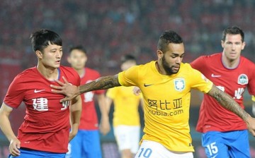Jiangsu Suning winger Alex Teixeira (in yellow shirt) competes for the ball against two Henan Jianye defenders.