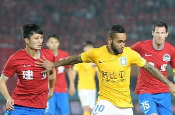 Jiangsu Suning winger Alex Teixeira (in yellow shirt) competes for the ball against two Henan Jianye defenders.