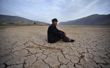 A villager sits alone on a dried-up riverbed in Gulang County on July 15, 2009 in Gansu Province, northwest China.
