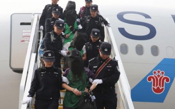 Police escort a group of people wanted for suspected fraud in China after they were deported from Kenya.