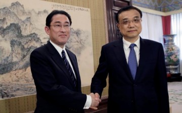 Japanese Foreign Minister Fumio Kishida poses with Chinese Premier Li Keqiang during their meeting in Beijing on Saturday, April 30.