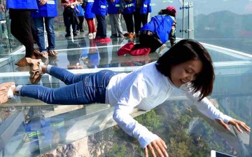 A female tourist lie on the glass sightseeing platform.