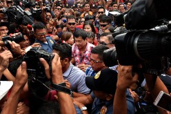 Presidential candidate Rodrigo Duterte (center) flocked by supporters and members of the media while on his way to cast his vote in a polling precinct on May 9, 2016 in Davao City, Philippines.