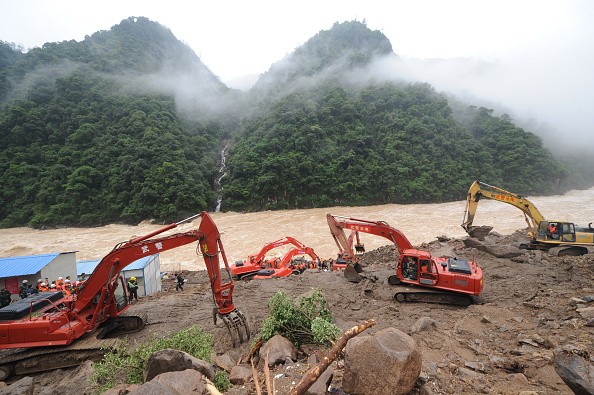 Rescuers use heavy machinery to search for signs of life in the Fujian landslide site.