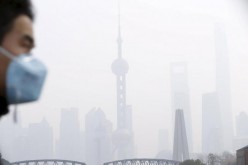 A man wearing a face mask walks on a bridge in front of the financial district of Pudong amid heavy smog in Shanghai, China.