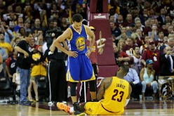Stephen Curry is standing over the fallen LeBron James during a game.