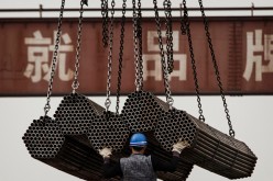 A Chinese steel worker helps load steel rods onto a large truck for transport at a plant on April 6, 2016 in Tangshan, Hebei province, China. 