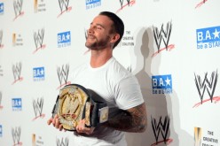 CM Punk smiles at the cameras while posing with his WWE championship belt.