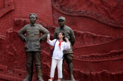 A girl takes a selfie with statues depicting late Chinese chairman Mao Zedong (L) and former general Zhu De.