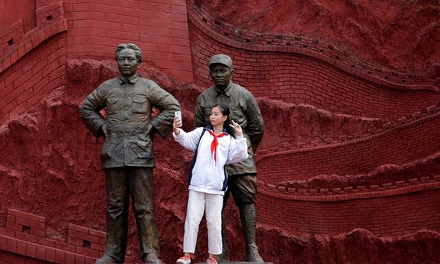 A girl takes a selfie with statues depicting late Chinese chairman Mao Zedong (L) and former general Zhu De.