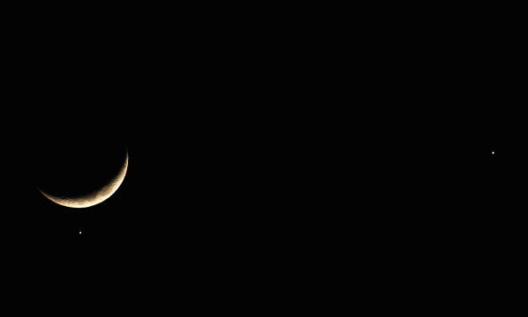 The planet Venus appears close to the crescent Moon as Jupiter (R) appears nearby during a rare planetary alignment on December 1, 2008 in Brighton, England.