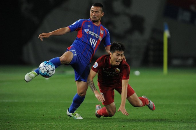 Shanghai SIPG defender Fu Huan falls against FC Tokyo's Takuma Abe during their ACL knockout phase match.
