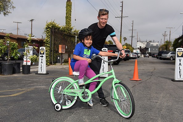 Member of team Sky Danny Van Poppe met kids from the Boys & Girls Club of South Bay test out their new bicycles in an interactive cycling course.