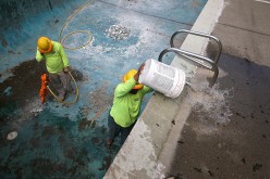 ZL Construction worker Raul Buenrostro (R) bails water out from a pool as co-worker Alex Hernandez (L) prepares to operate a jackhammer during the demolition of a swimming pool at an apartment complex on April 8, 2015 in Hayward, California.