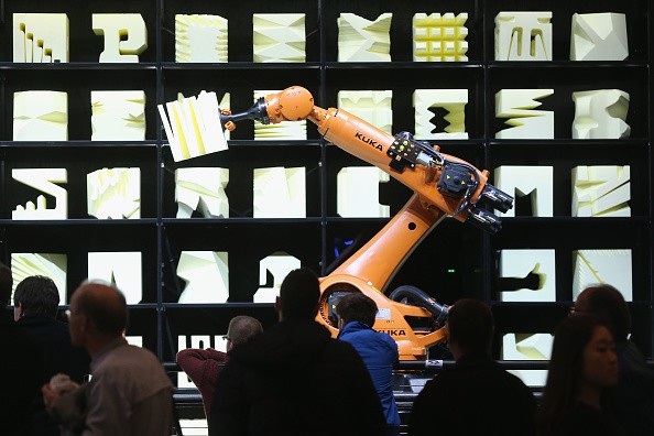 Visitors watch a Kuka robot perform precise movements at a technology trade fair on March 16, 2015 in Hanover, Germany.