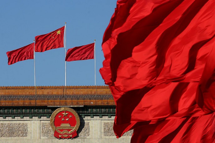 Red flags flutter in the wind near the Chinese national emblem outside the Great Hall of the People.