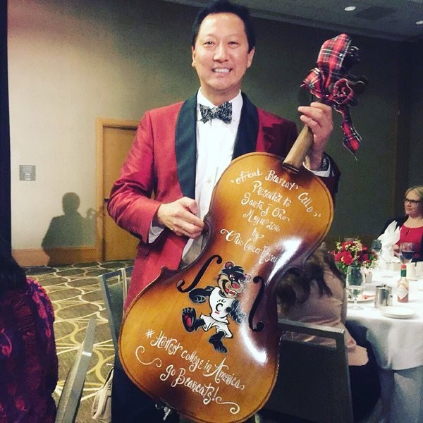 Santa Ono, the University of Cincinnati president who admitted his past battle with depression stands with his best trophy ever, a Cello trophy.