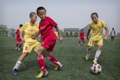 Young Chinese students play during a match on a practice pitch at the Evergrande International Football School on June 14, 2014 near Qingyuan in Guangdong Province, China.