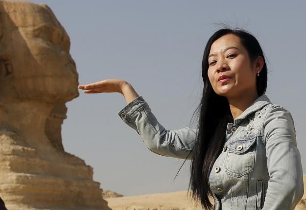 A Chinese tourist poses for a photo of the Sphinx at the Giza Pyramids in Egypt.