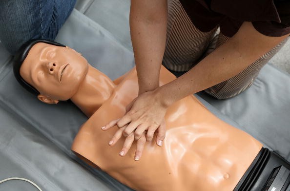 A woman performs chest compressions on a mannequin while learning C.P.R. on the steps of San Francisco city hall following a press conference celebrating the 50th anniversary of lifesaving by using C.P.R.