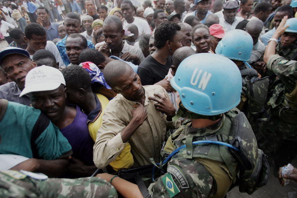 A United Nations peacekeeper holds back voters as they try to form a line in front of a polling center on Feb. 7, 2006 in Port-au-Prince, Haiti.